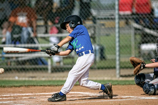 Youth baseball player in team jersey swinging at home plate